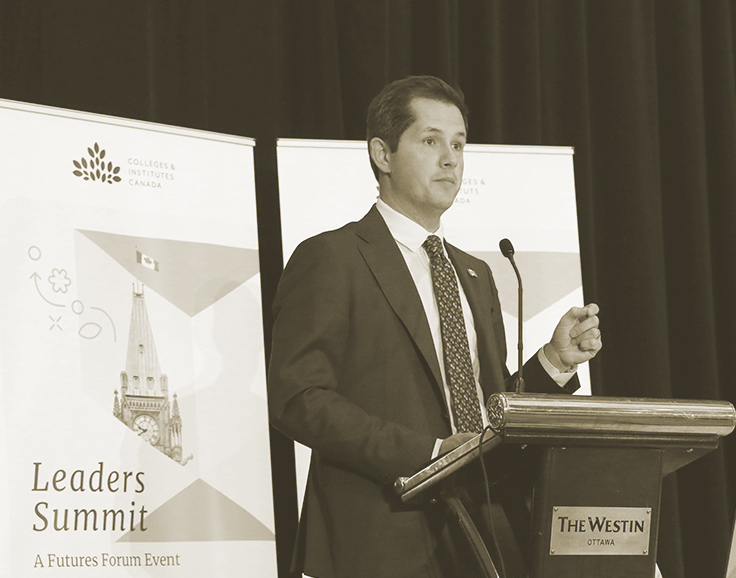 A speaker stands at the conference podium