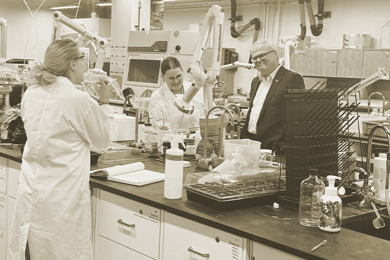 A group of people conversing inside a lab at Loyalist College